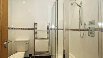 Ein modernes Badezimmer mit Toilette, einer Duschkabine und einem Handtuchhalter.