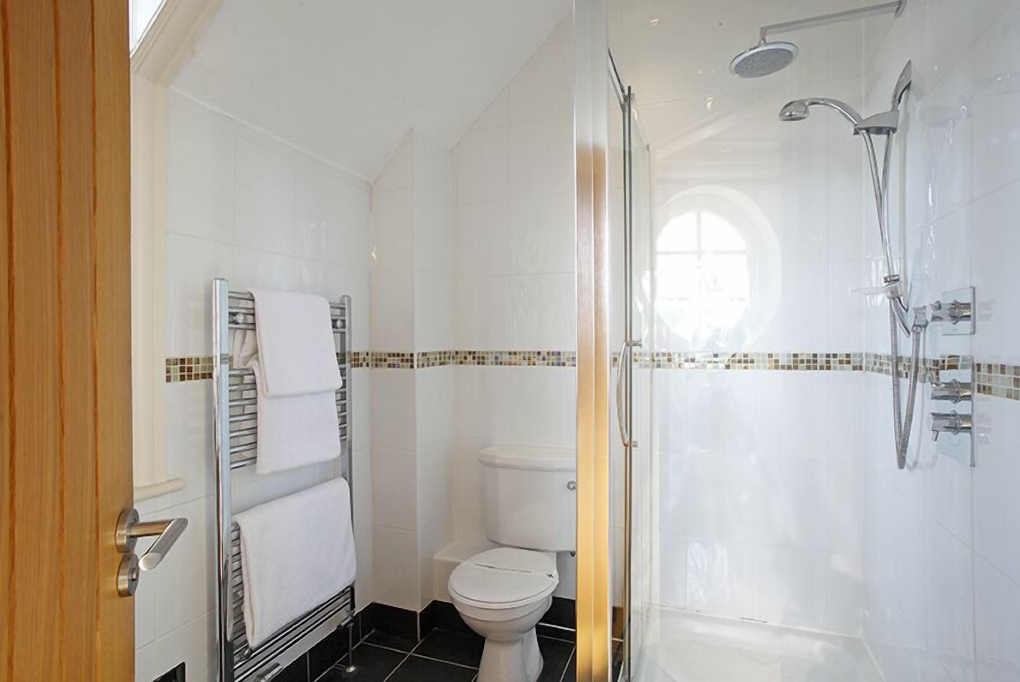 Ein modernes Badezimmer mit Duschkabine aus Glas, einer weißen Toilette und einem Handtuchhalter.