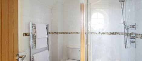 Ein modernes Badezimmer mit Duschkabine aus Glas, einer weißen Toilette und einem Handtuchhalter.
