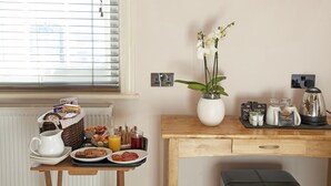 A breakfast setup with a wicker basket, plates of food, a pitcher, and a vase with white orchids. - Castle Hotel (Aberystwyth)