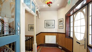 A hotel corridor with wooden paneling, a radiator, and framed pictures on the walls. - Castle Hotel (Aberystwyth)