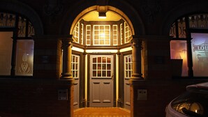 A hotel entrance with a double door, a small balcony with a light fixture, and a sign above the door. - Castle Hotel (Aberystwyth)
