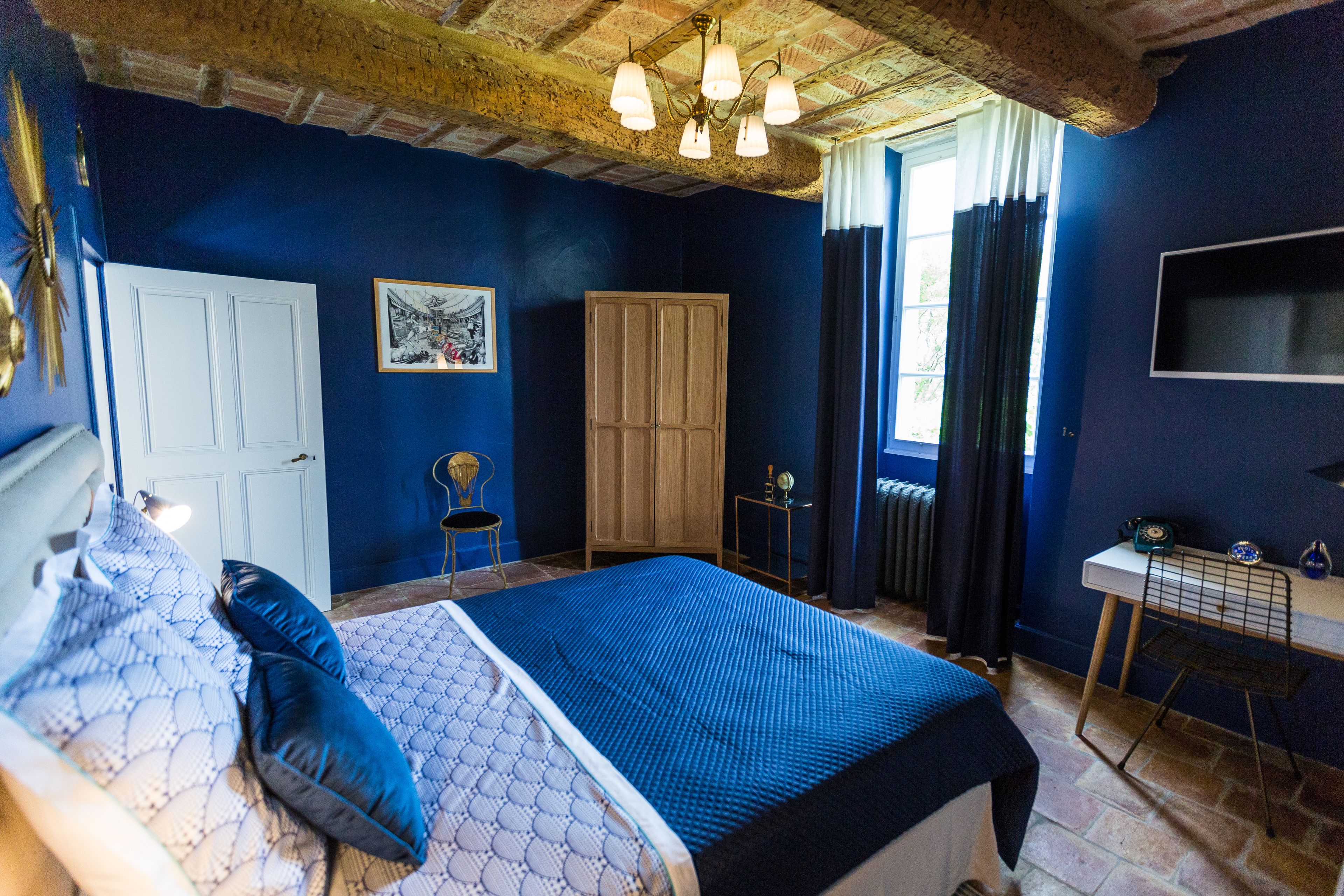 A bedroom with a bed, a wardrobe, a desk, and a television.