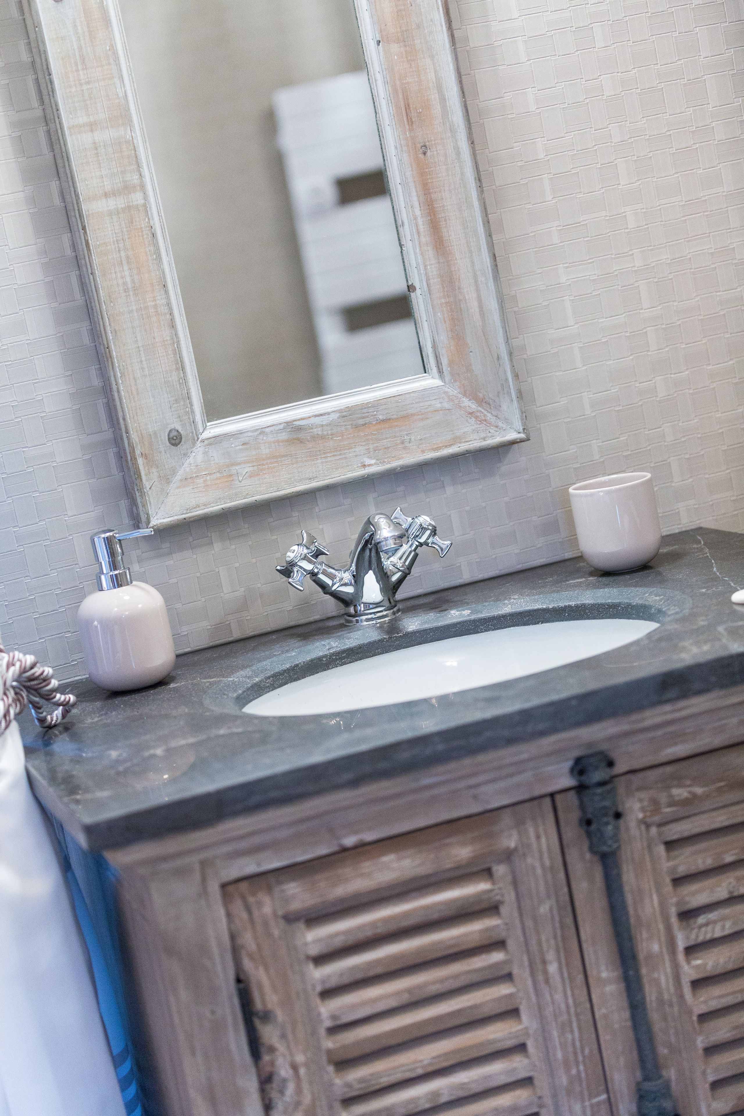 Un baño con lavamanos, espejo y muebles de madera.