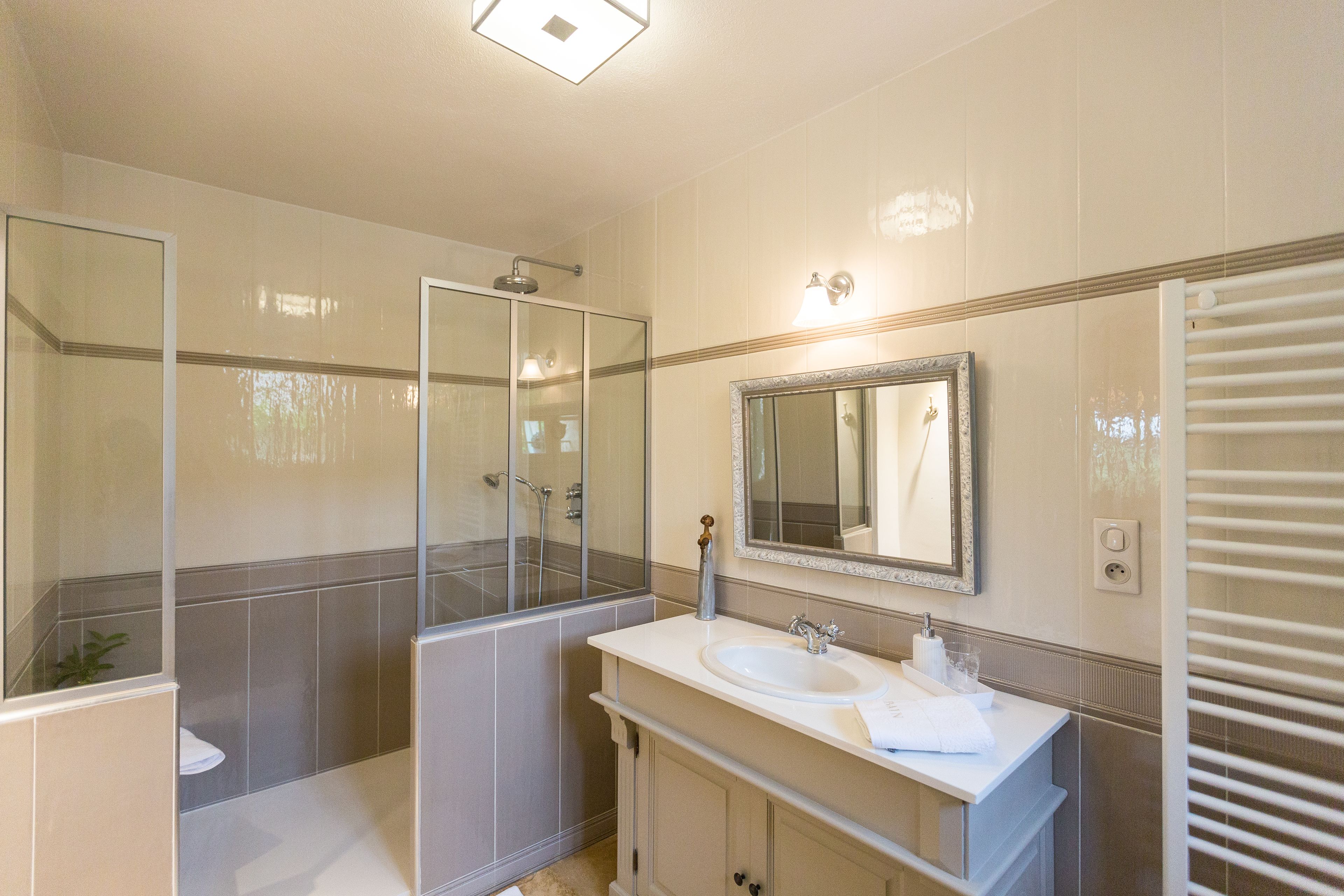 Une salle de bain moderne dotée d’une douche à parois de verre, d’un meuble-lavabo à deux vasques et d’un grand miroir.