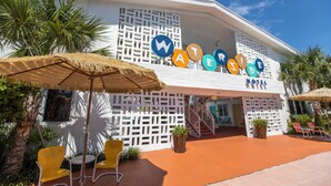 A hotel named "WATER SIDE" with a white facade, outdoor seating area, and palm trees.