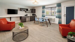 A modern living room with a sofa, a coffee table, and a dining area with chairs and a table.