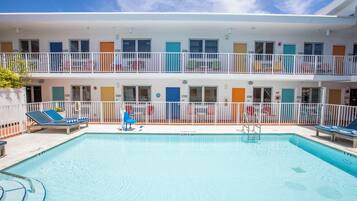 A two-story hotel with a swimming pool, balconies, and a variety of room colors.