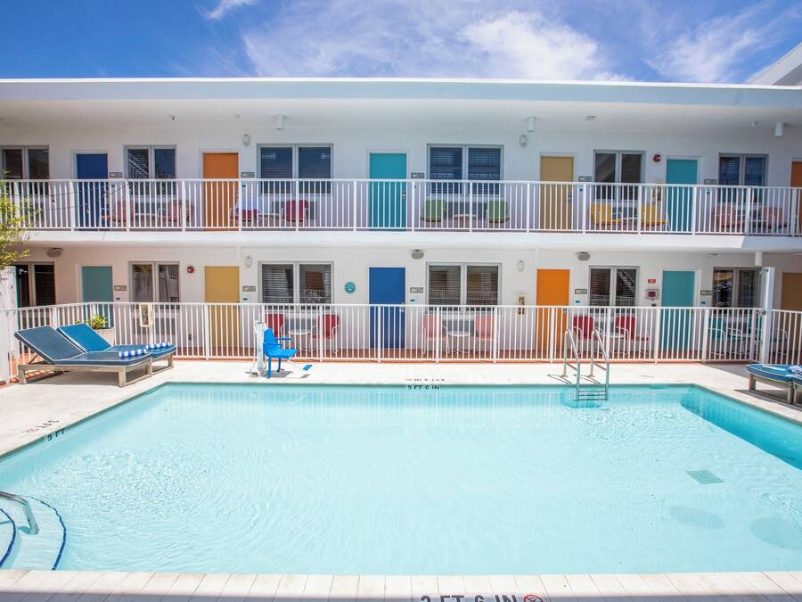 A two-story hotel with a swimming pool, balconies, and a variety of room colors.