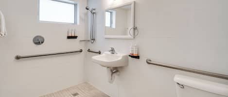 Un baño con lavamanos blanco, espejo, ducha e inodoro.