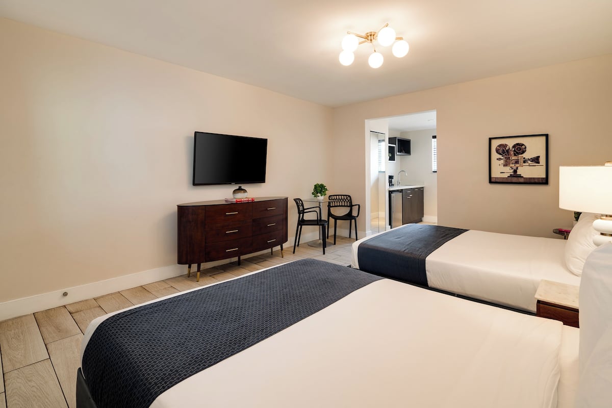 A hotel room with two beds, a TV, a desk, and a chair.
