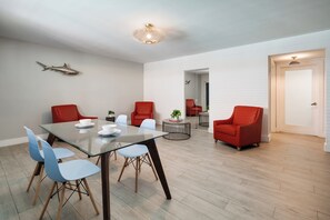 Una sala de estar moderna con una mesa de comedor de vidrio, sillas rojas y un sofá rojo.