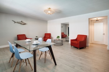 A modern hotel room with a glass dining table, two beds, a desk, and a large window with curtains. at Waterside Hotel and Suites