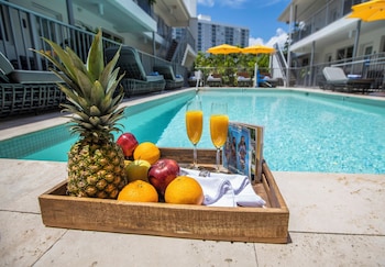 A modern living room with a sofa, a coffee table, and a dining area with chairs and a table. at Waterside Hotel and Suites