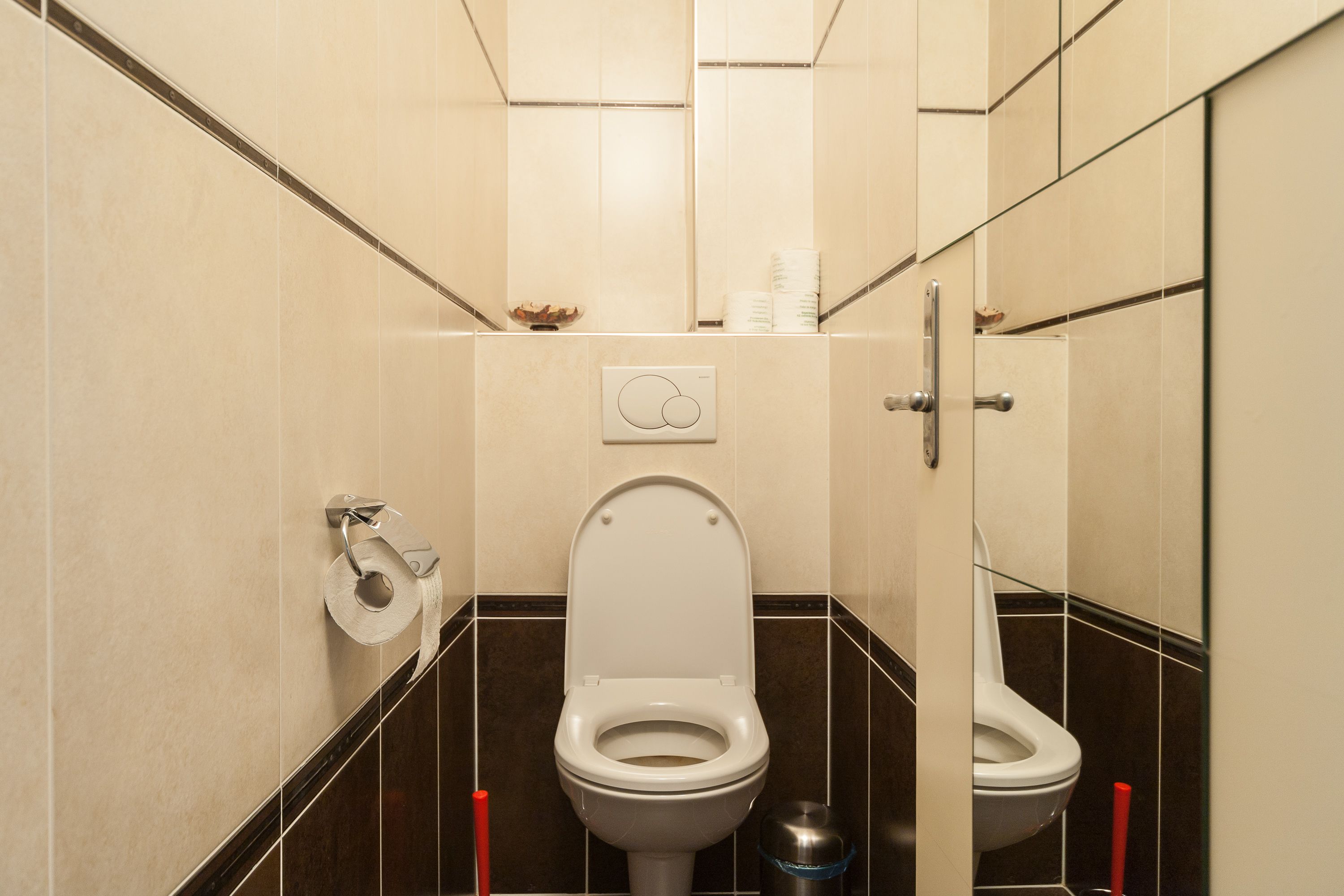 Une salle de bain moderne équipée de toilettes, d’une poubelle et d’un sèche-mains.