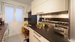 A modern kitchen with stainless steel appliances, a built-in oven, and a large window with blinds.