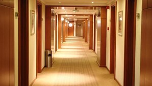 A hotel corridor with wooden doors, a trash bin, and a carpeted floor. - Lavender Hotel Sharjah (Sharjah)