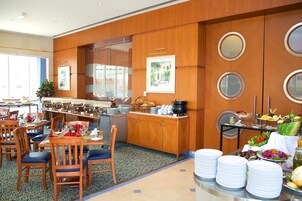 A hotel dining area with wooden paneling, a buffet setup, and a view of the outdoors.