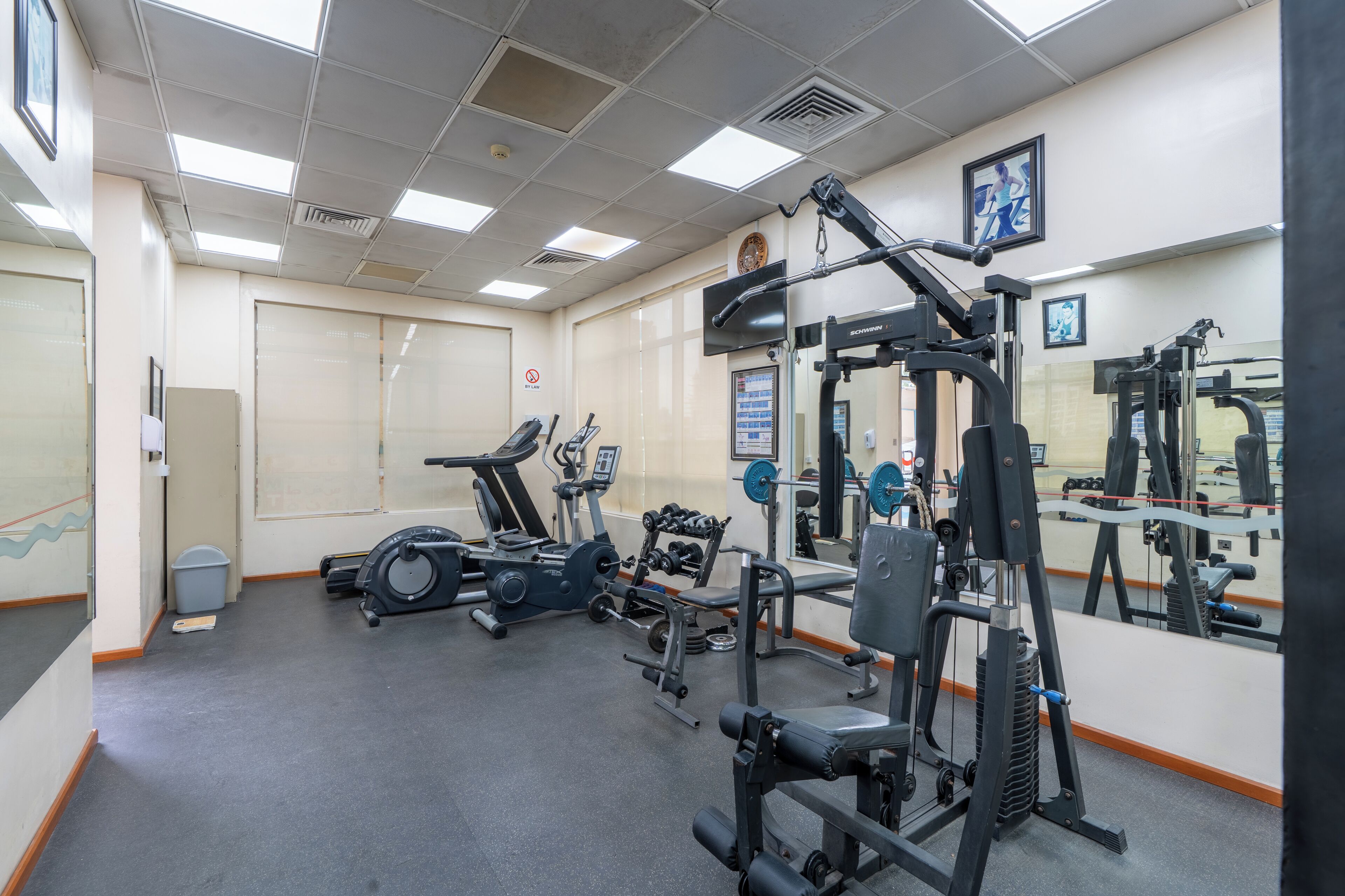 Un gimnasio con equipo de ejercicio, un espejo y una puerta.