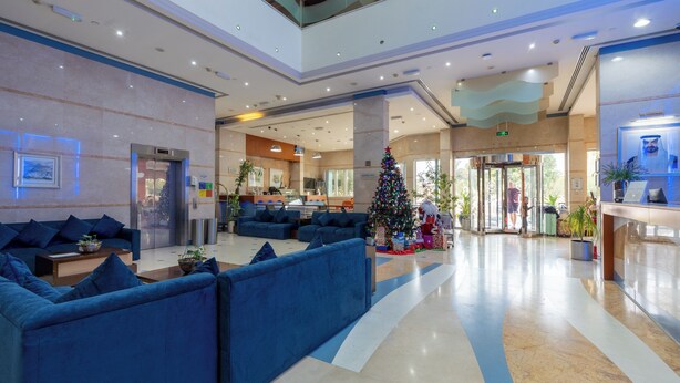 A spacious lobby with blue seating, a Christmas tree, and a reception desk. - Lavender Hotel Sharjah (Sharjah)