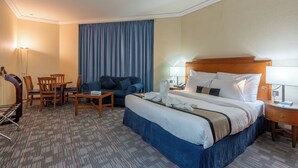 A hotel room with a large bed, a desk, a chair, a sofa, and a dining table. - Lavender Hotel Sharjah (Sharjah)