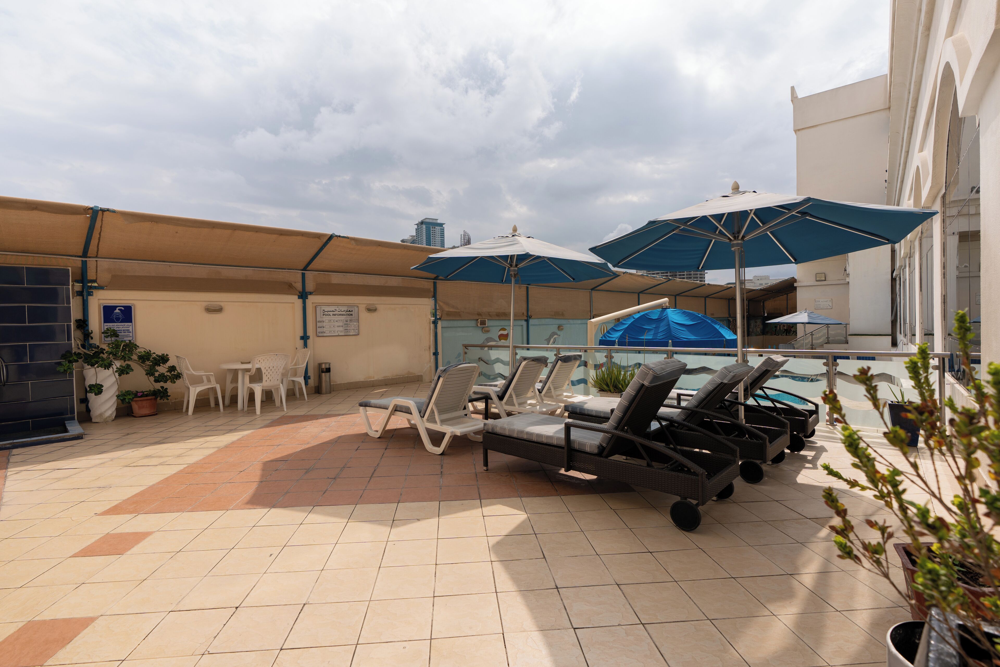 Área externa coberta com espreguiçadeiras, guarda-sóis e piscina.