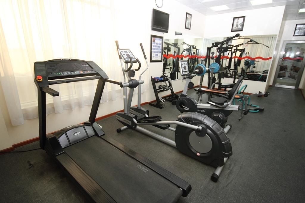 A gym with treadmills, weight machines, and a mirror wall.