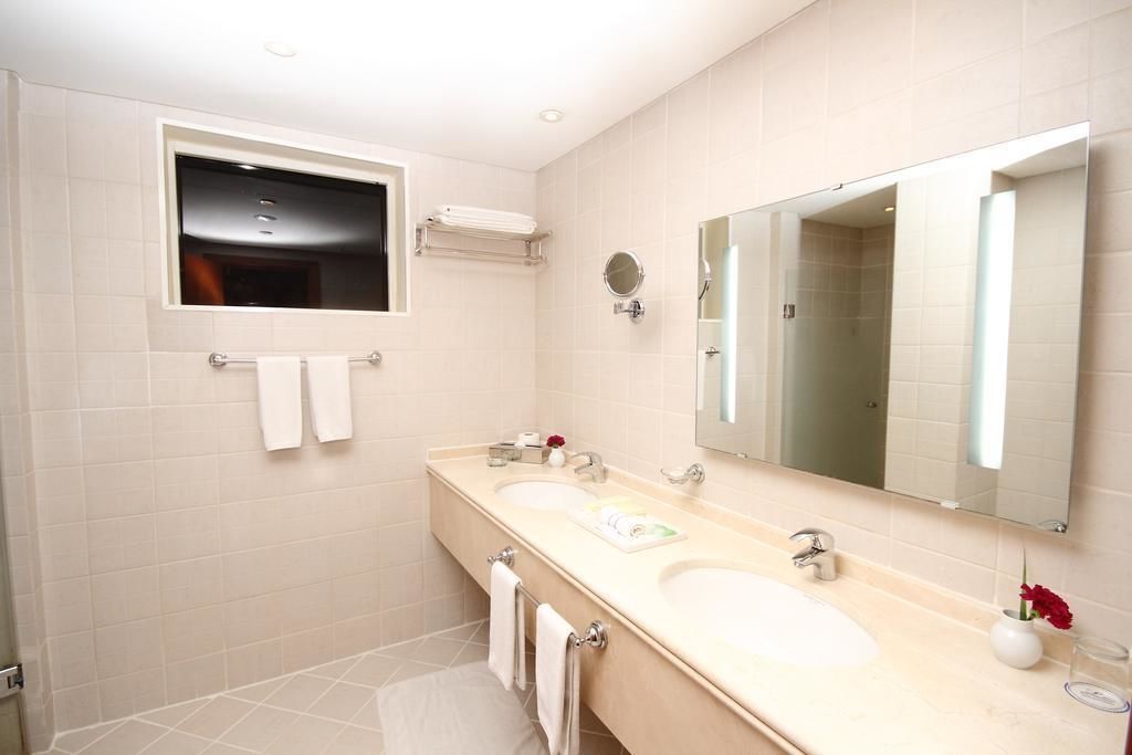 A modern bathroom with two sinks, a large mirror, and a towel rack.