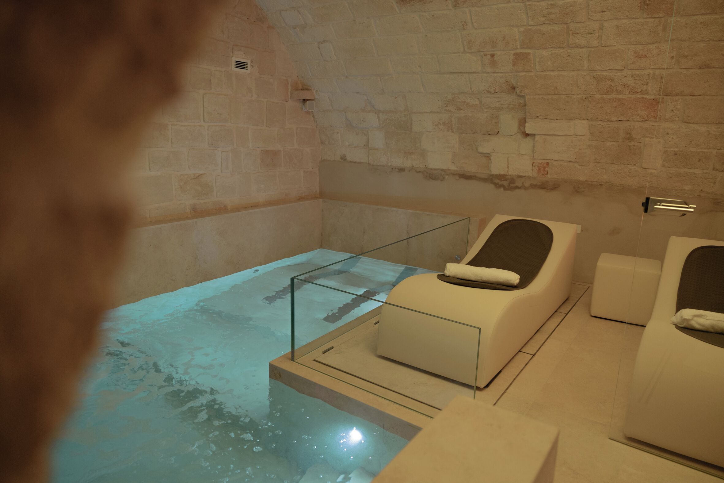 A spa room with a glass-enclosed hot tub, a massage chair, and a separate relaxation area.
