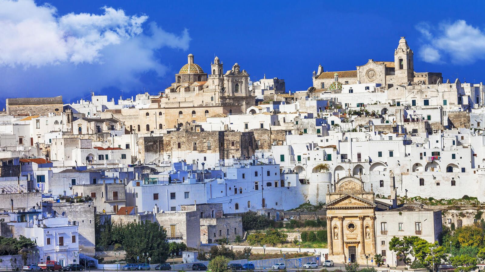 A densely packed hillside town with historic architecture, including a prominent church and a bell tower.