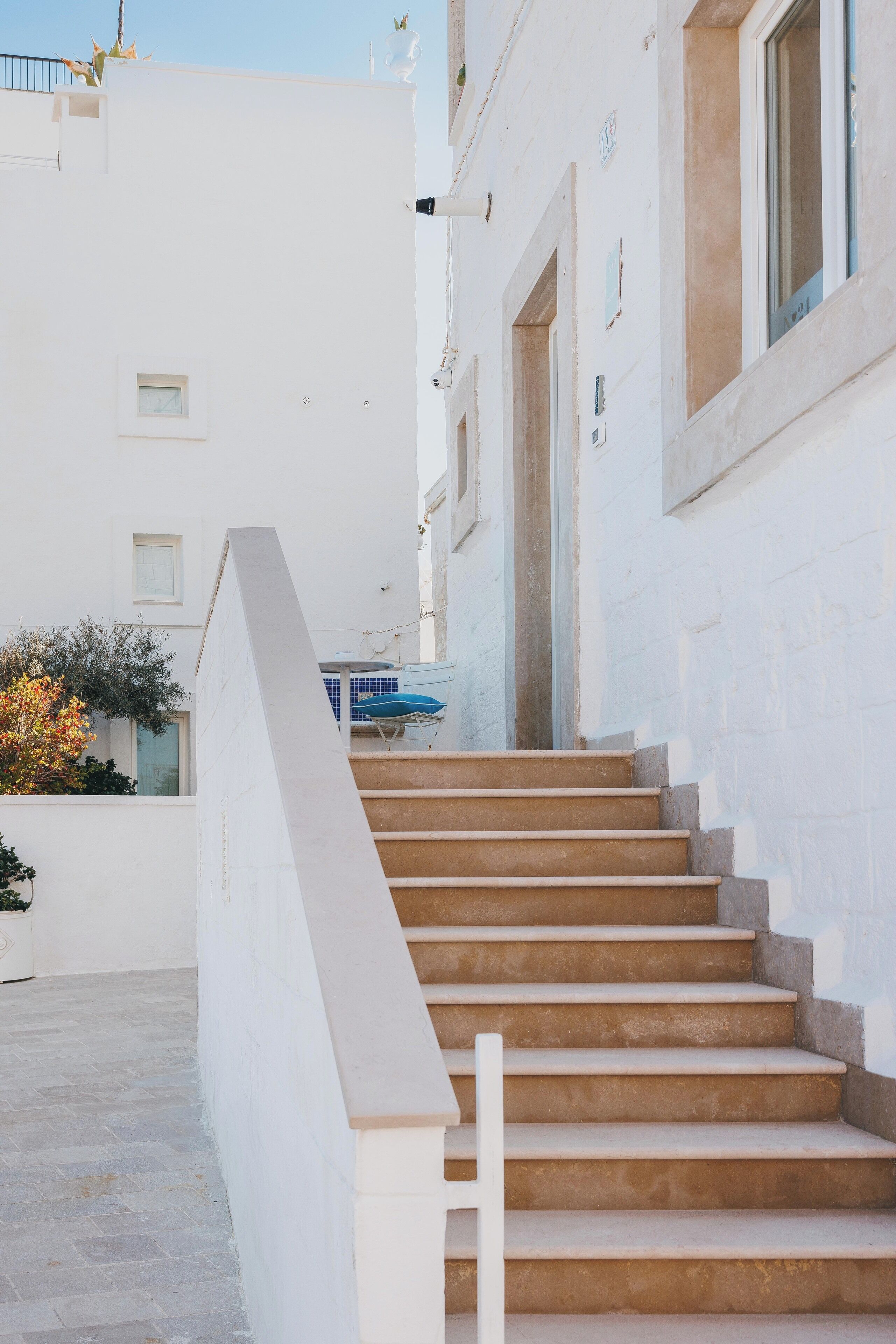 Un escalier beige mène à un bâtiment blanc doté d’un balcon.