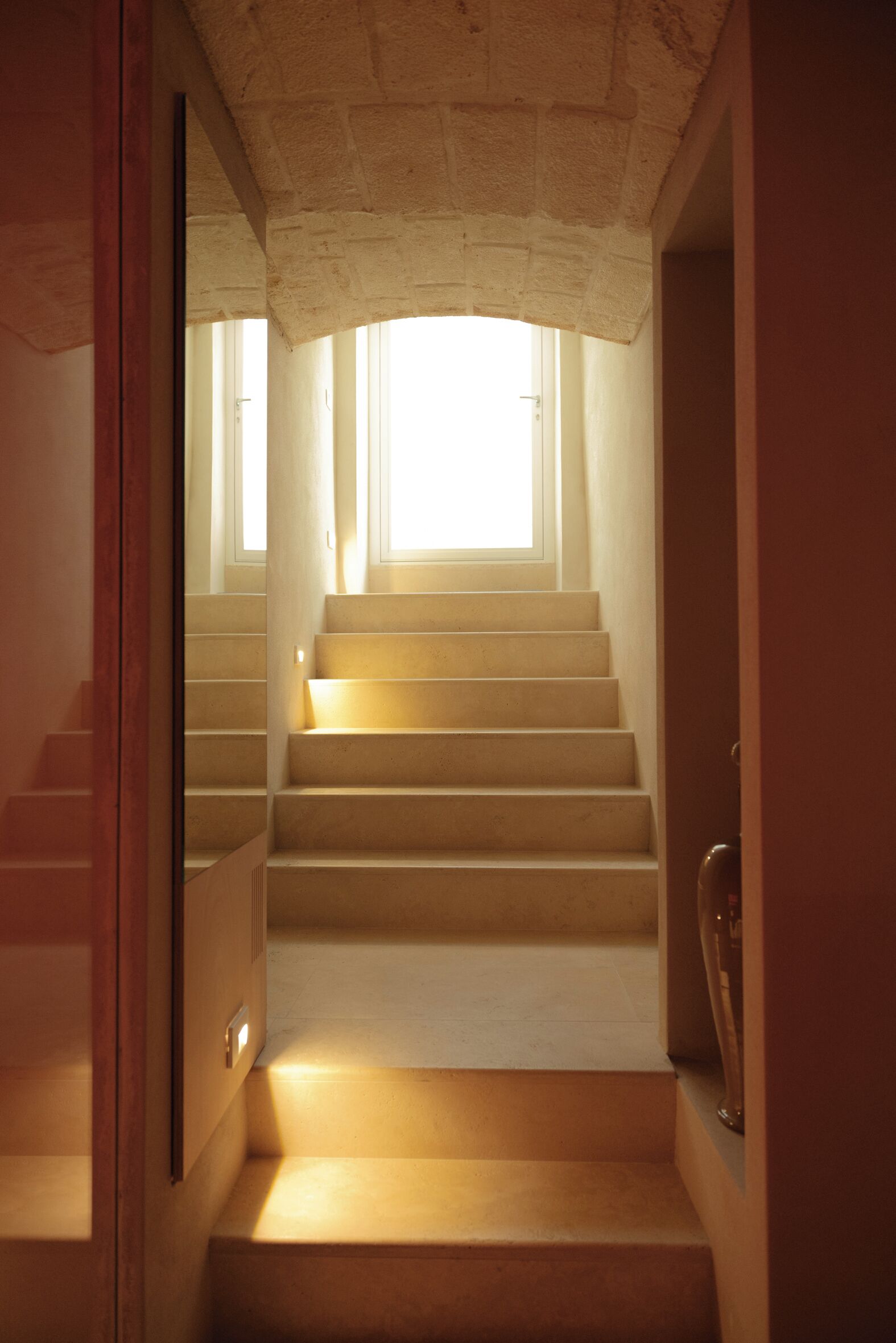 Una escalera que conduce a una habitación luminosa con una ventana.