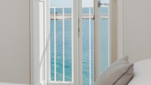 A bedroom with a view of the sea through a large window. - Santa Maria 24 - Luxury Apartments (Monopoli)