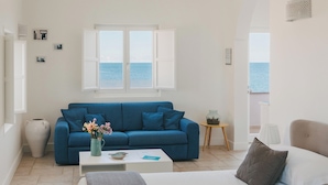 A bedroom with a bed, a sofa, and a view of the sea through a window. - Santa Maria 24 - Luxury Apartments (Monopoli)