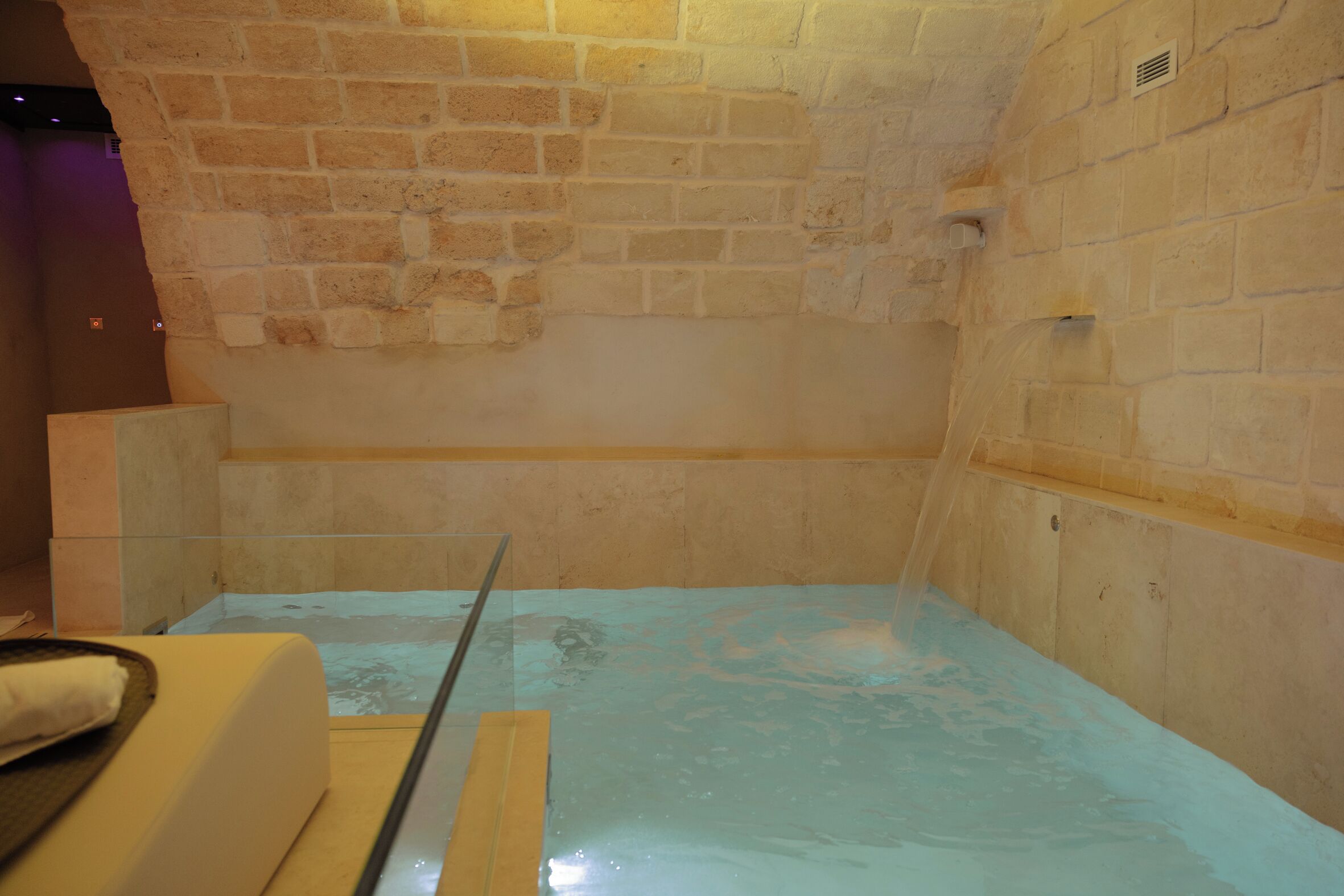 Una habitación con separador de vidrio, pared de ladrillo y suelo de baldosas.