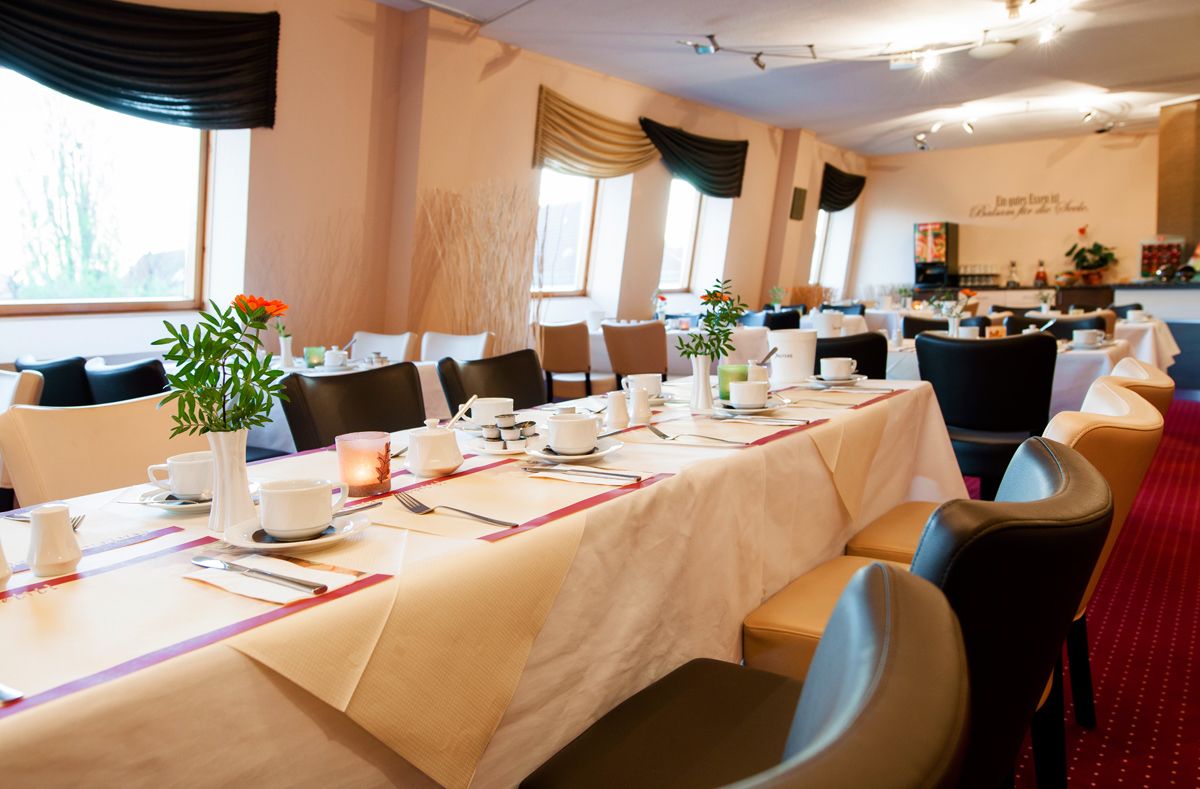 Un salón de conferencias con varias mesas dispuestas para una reunión, equipado con sillas, mesas y diversos útiles de oficina.