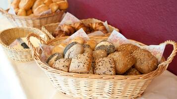 A table with baskets of various breads and pastries.