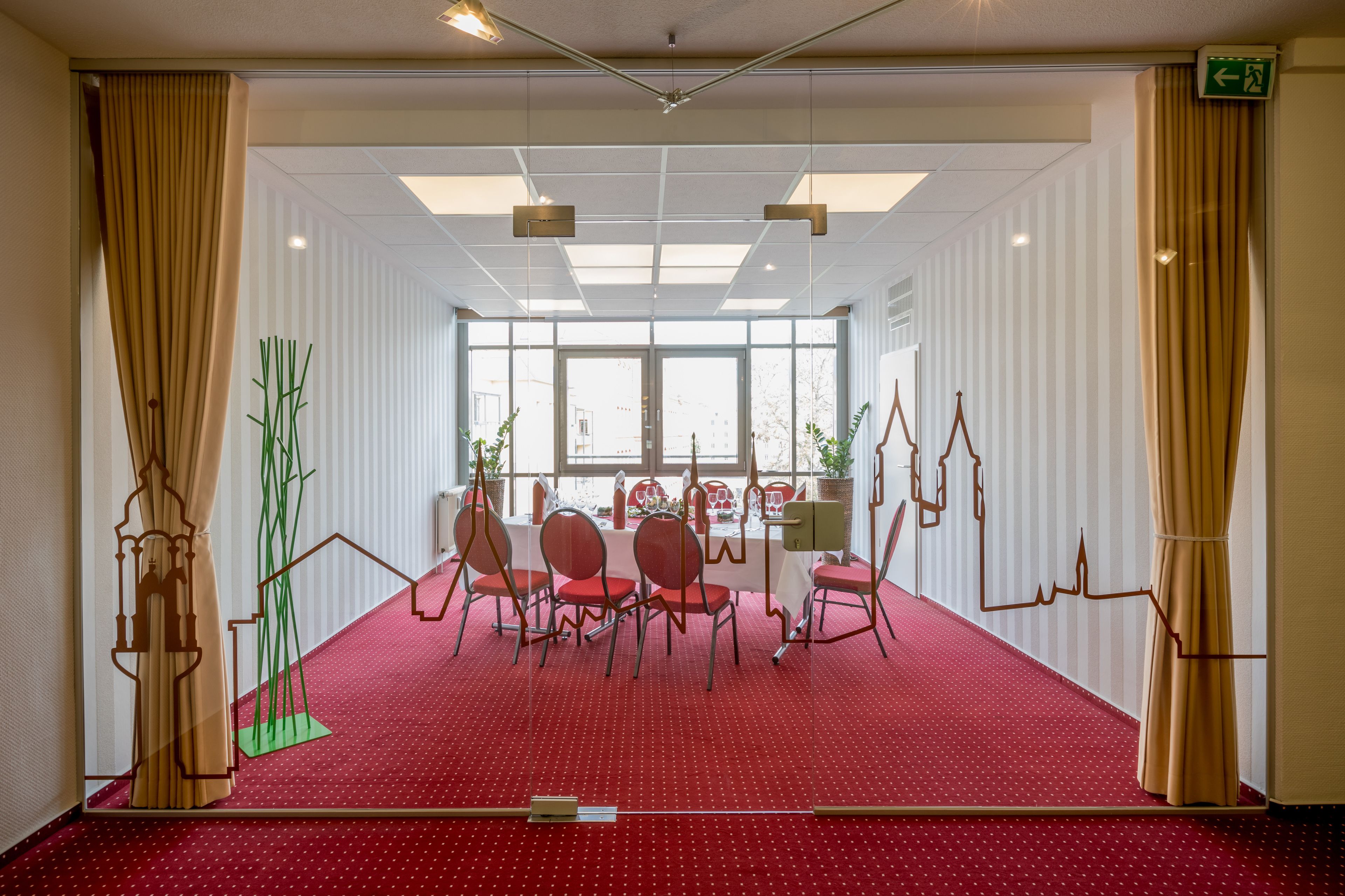 Una sala de conferencias con alfombra roja, paredes blancas y ventanas amplias.
