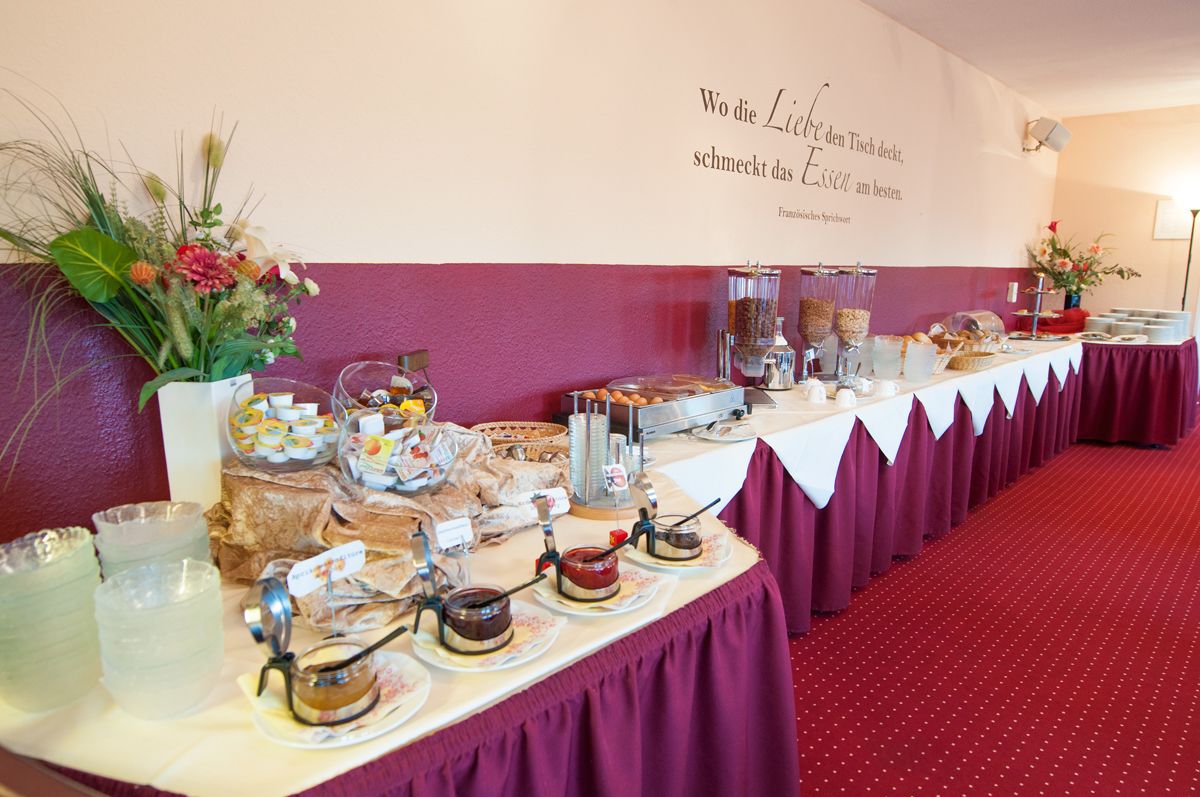 A buffet table with various food items and a decorative wall with a quote.