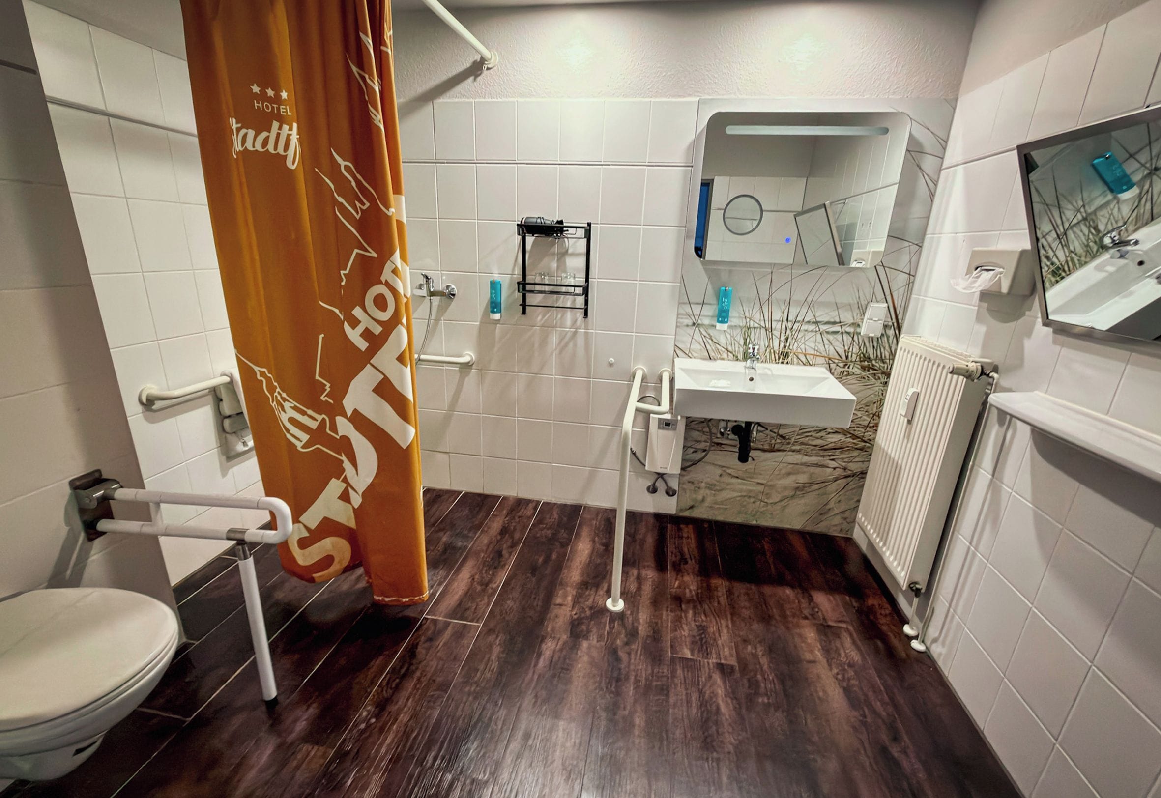 Een moderne badkamer met douchegordijn, toilet, wastafel en spiegel.
