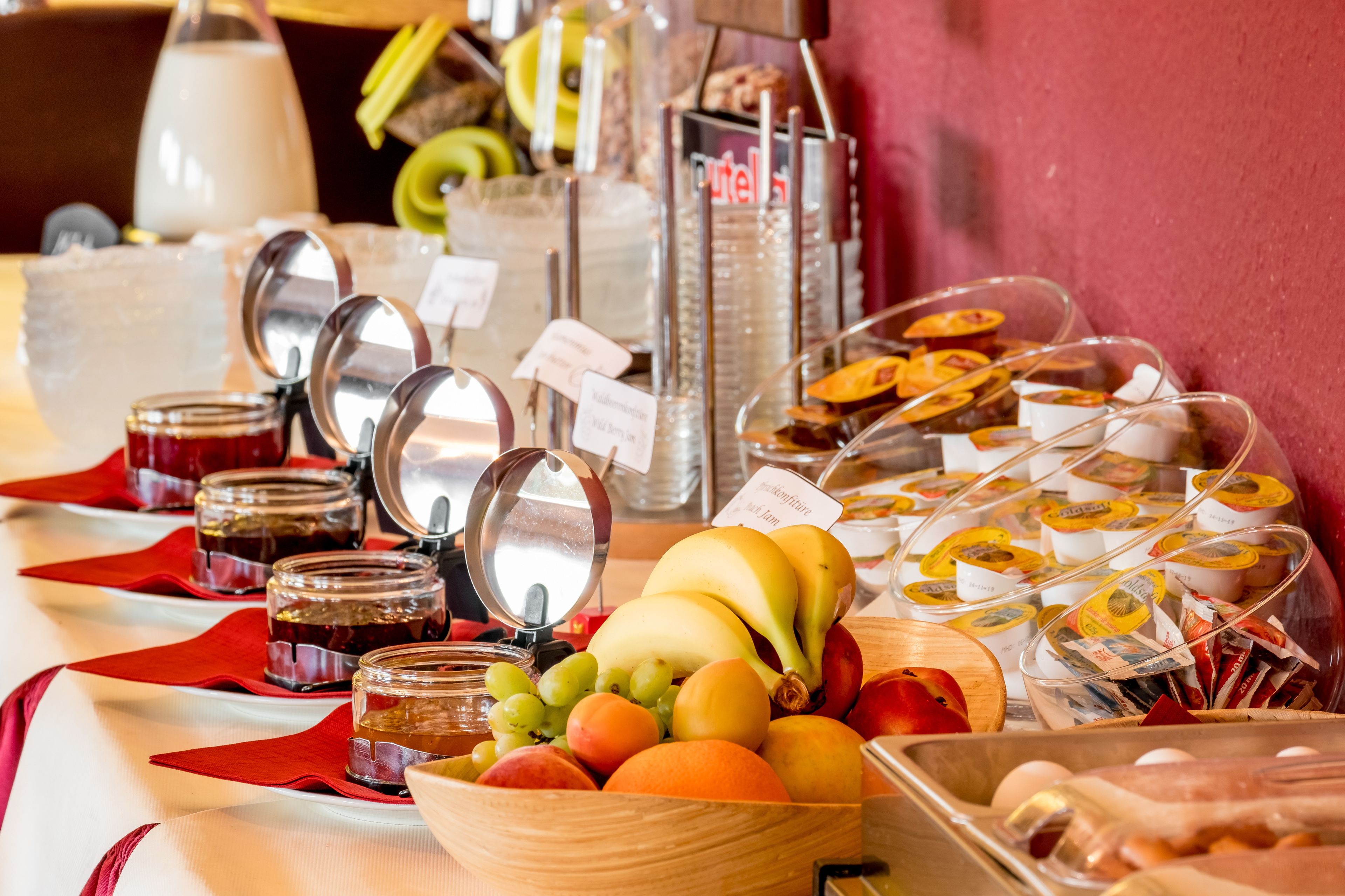 Un bufé con diversas frutas, mermeladas y alimentos envasados.