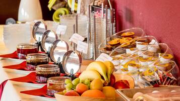 Un bufé con diversas frutas, mermeladas y alimentos envasados.
