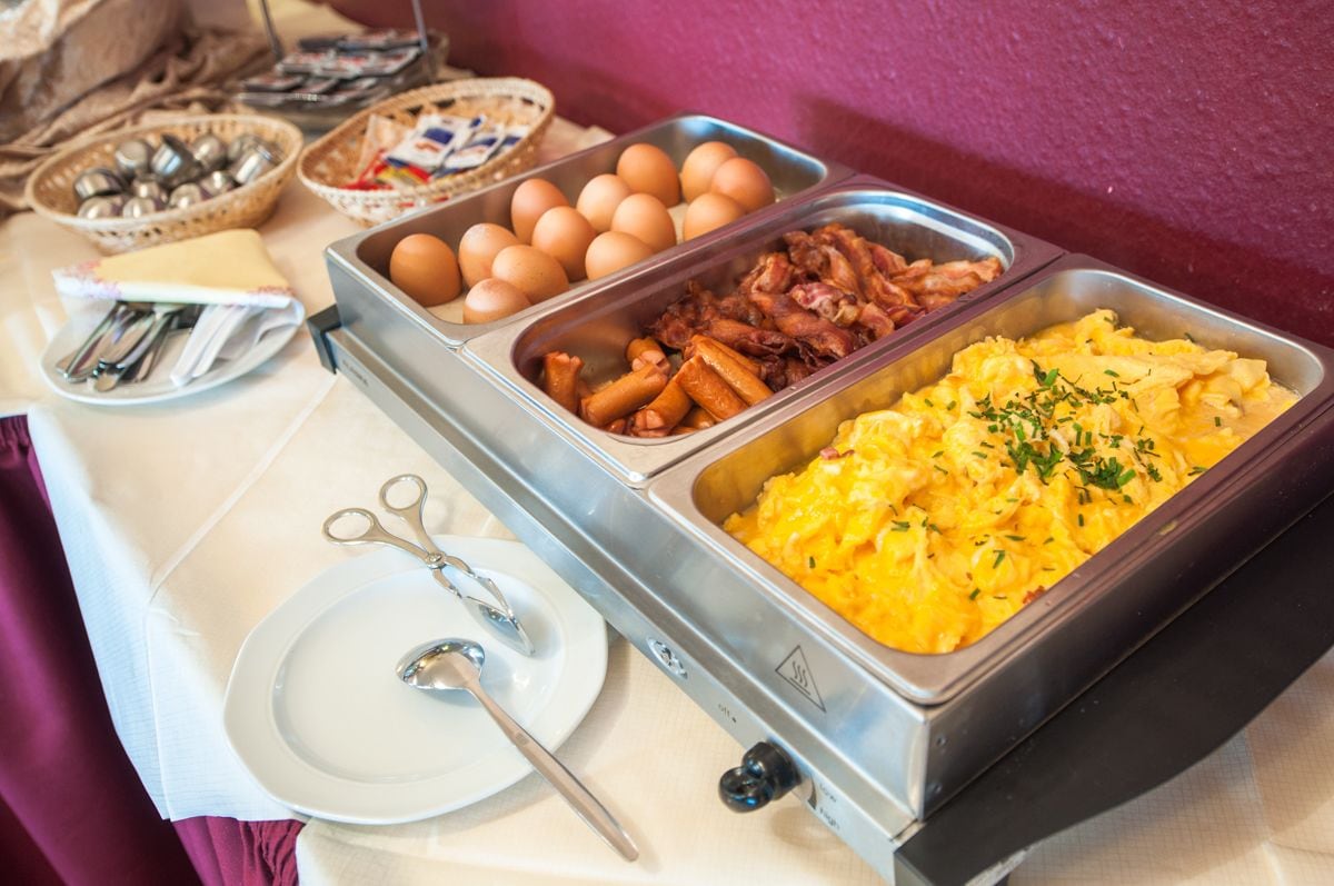 A buffet with various food items including eggs, bacon, and scrambled eggs.