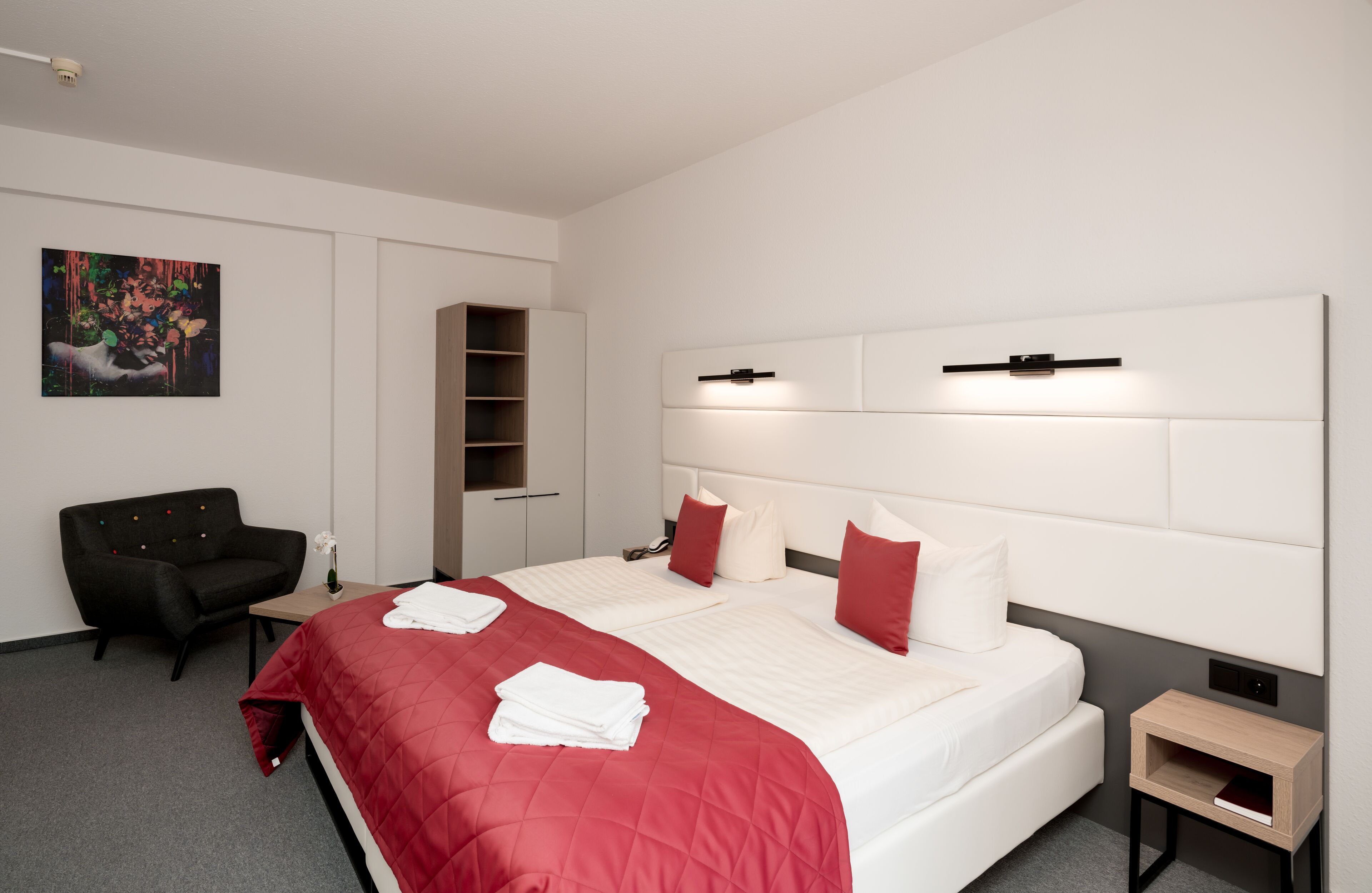 Una habitación de hotel moderna con una cama grande, un escritorio, una silla y una mesita.