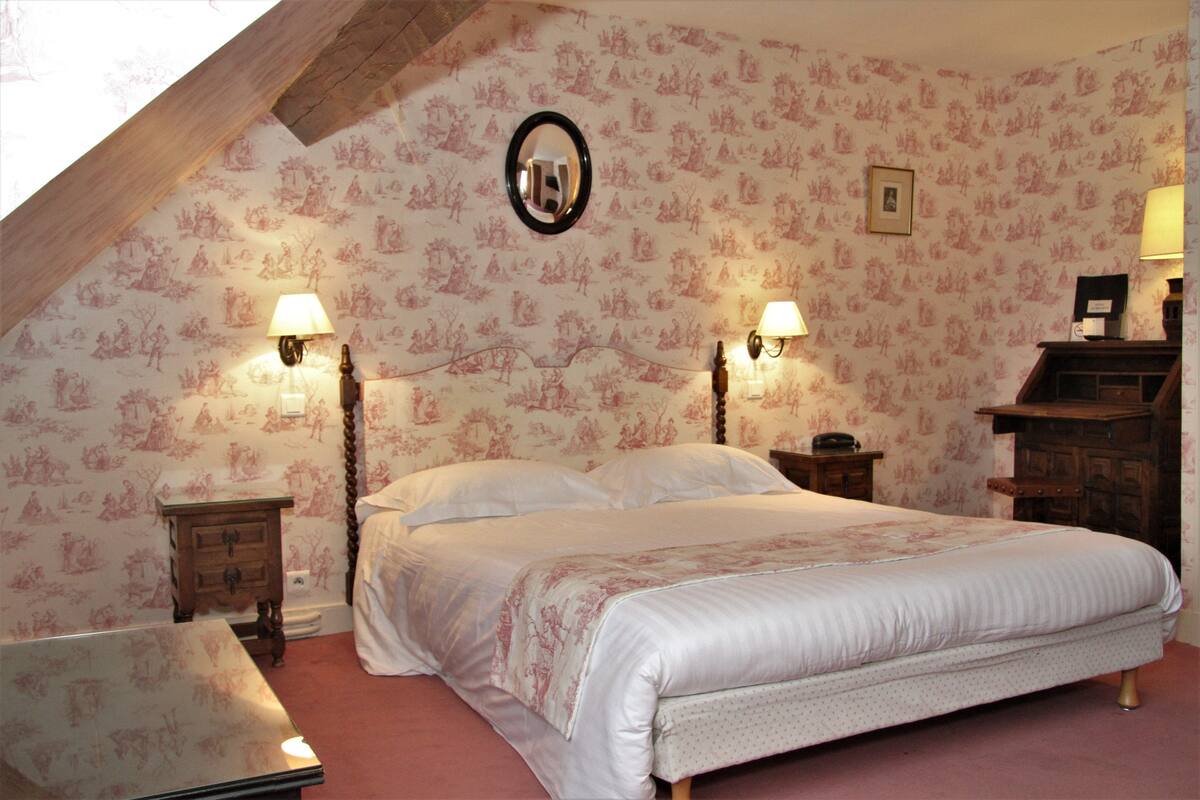 Ein Schlafzimmer mit einem großen Bett, zwei Nachttischen mit Lampen, einem Spiegel an der Wand und einer Kommode.