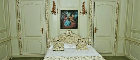 Un dormitorio con una cama grande, papel tapiz floral y dos puertas.