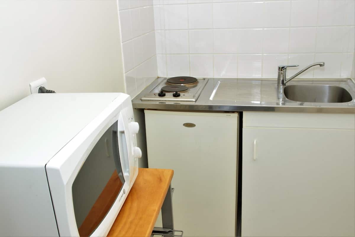 Eine kleine Küche mit Mikrowelle, einem kleinen Kühlschrank und einem Spülbecken.