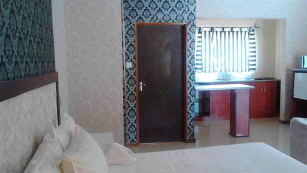 A hotel room with a bed, a desk, and a window with blinds.