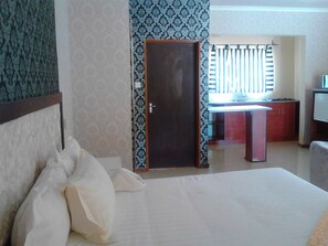 Ein Hotelzimmer mit Bett, Schreibtisch und einem Fenster mit Jalousien.