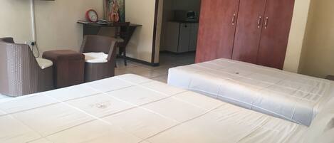 Habitación de hotel con una cama, una silla, una mesita, un televisor montado en la pared y un armario.